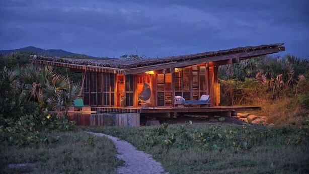 A modern house with a large deck, surrounded by lush greenery and a clear view of the sky.