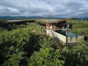Un chalet rustique doté d’une piscine, entouré d’une végétation luxuriante et avec des montagnes en toile de fond.