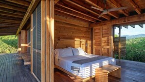 Eine Holzhütte mit einem Bett, einem Deckenventilator und einer Terrasse.