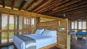 A wooden-framed room with a bed, a dining table, and chairs.