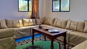A corner room with a sofa, a table, and a patterned rug.
