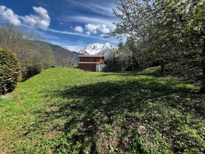 A chalet with a balcony, surrounded by a grassy slope and trees, with a mountain in the background. - Chalet, terrace, balcony, tv, ski locker, 38m², Saint Gervais (Saint-Gervais-les-Bains)