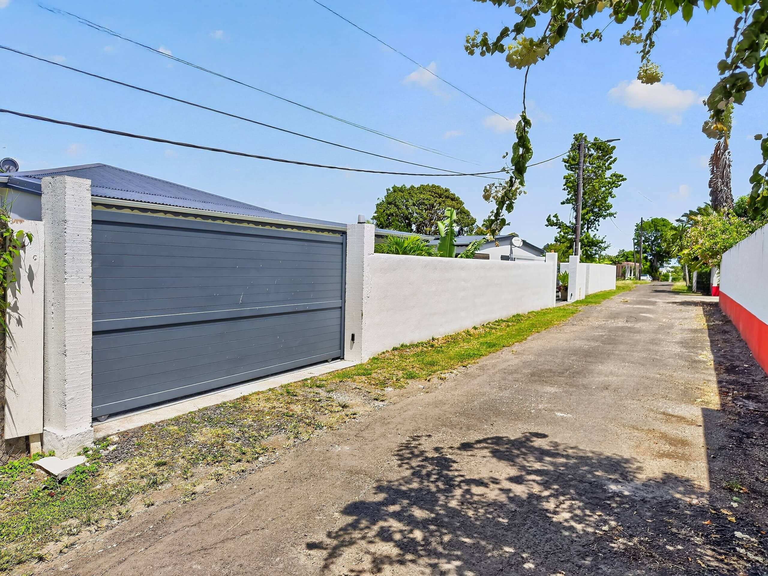 Une rue résidentielle avec une porte de garage fermée, un trottoir en béton et un ciel dégagé.