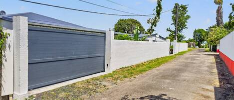 Une rue résidentielle avec une porte de garage fermée, un trottoir en béton et un ciel dégagé.
