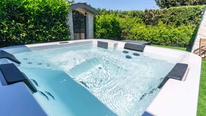 A hot tub with a stone wall and greenery in the background. - EDEN LUXURY ROOMS & GARDEN (Modugno)