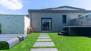 A modern house with a paved pathway leading to a glass door, a stone wall, and a small outdoor seating area. - EDEN LUXURY ROOMS & GARDEN (Modugno)