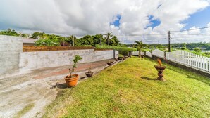 A garden with potted plants, a white fence, and a concrete wall.