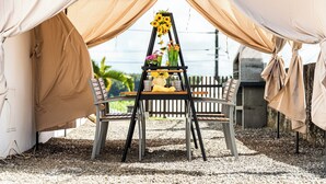 A tent with a table and chairs, a flower arrangement, and a view of the outdoors.