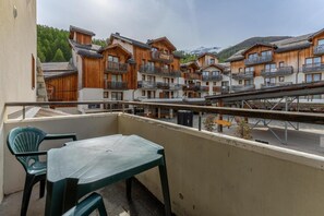 Ein Balkon mit Tisch und Stühlen, mit Blick auf eine Reihe von Holzhäusern mit Balkonen.