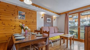 A wooden interior with a dining table set, a sofa, and a view through a window. - 40m from ski slopes, 1st floor, fitness, swimming pool, sauna, balcony, tv, ski locker, 34m² (Les Orres)