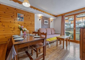Ein Holzinnenraum mit Essplatz, einer Couch und Blick durch ein Fenster.