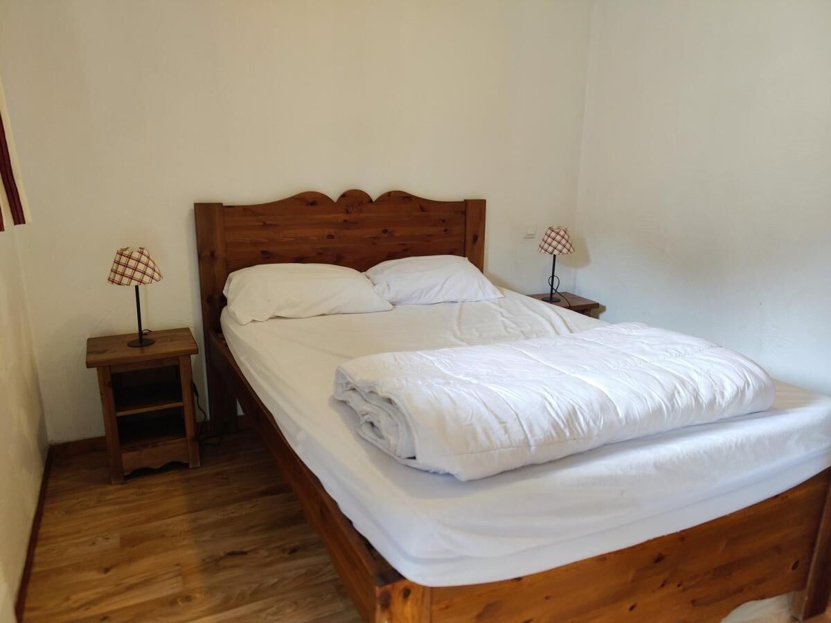 A single bed with a wooden headboard, two bedside tables with lamps, and a wooden floor.