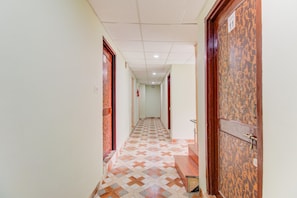 Un pasillo con suelo estampado, puertas de madera y techo con azulejos.