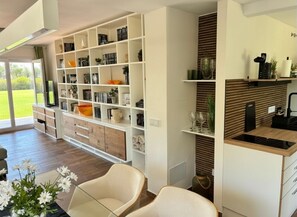A modern living room with a built-in bookshelf, a dining area with a table and chairs, and a kitchen area with a countertop and cabinets. - Luxurious apartment garden pool beach 300 meters view of Africa Gibraltar (La Línea de la Concepción)