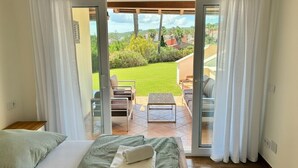 Un dormitorio con cama, una mesita y vista a un patio con mobiliario exterior.