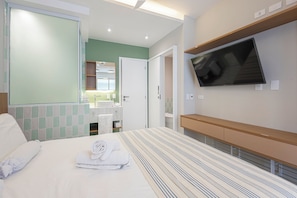 Ein Hotelzimmer mit Bett, Fernseher, Badezimmer mit Spiegel und grüner Wand.