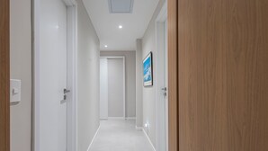 Ein Korridor mit weißen Wänden, einer Holztür rechts und einem gerahmten Bild an der Wand.
