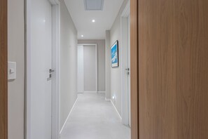 Ein Korridor mit weißen Wänden, einer Holztür rechts und einem gerahmten Bild an der Wand.