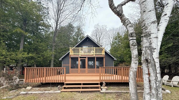 Een chalet met een houten terras, een balkon en een veranda.