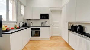 A modern kitchen with white cabinets, a black countertop, and a built-in oven. - Spacious Appartement 2br/7p - Nogent-sur-marne (Nogent-sur-Marne)