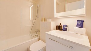 A modern bathroom with a bathtub, toilet, and vanity with a mirror. - Spacious Appartement 2br/7p - Nogent-sur-marne (Nogent-sur-Marne)