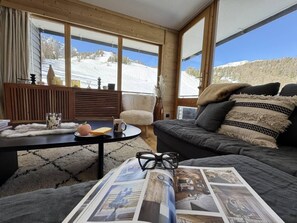A cozy living room with a sofa, a coffee table, and a chair. Large windows offer a view of a snowy mountain. - 4th floor, balcony, tv, ski locker, 62m², Vars (Vars)