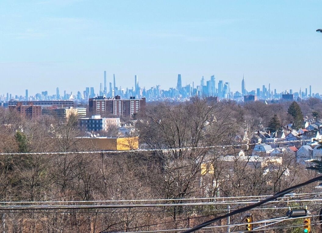 A city skyline with high-rise buildings, a mix of residential and commercial structures, and a clear sky.
