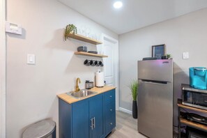 Una cucina compatta con lavello, mobili, frigorifero e macchina del caffè.