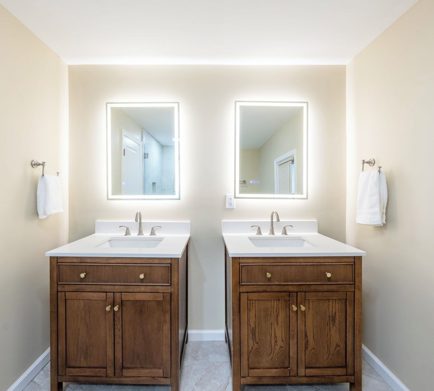 A bathroom with two sinks, wooden cabinets, and large mirrors.