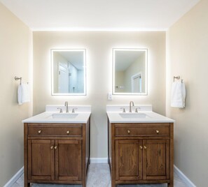Un bagno con due lavandini, mobili in legno e ampi specchi.
