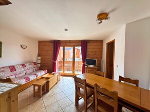 Um quarto acolhedor com um sofá de madeira, uma mesa de jantar e uma televisão.