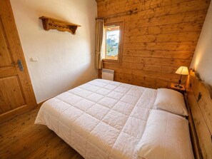 A wooden-paneled room with a bed, a window with curtains, and a wall-mounted shelf. - 2nd floor, balcony, tv, ski locker, 32m², Les Menuires (Les Menuires)