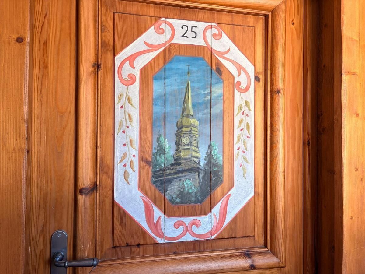 Una porta de fusta amb el número 25 i una representació pintada d'una torre.
