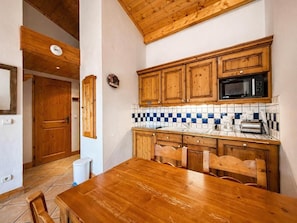 A kitchen with wooden cabinets, a microwave, and a tiled backsplash. - 2nd floor, balcony, tv, ski locker, 32m², Les Menuires (Les Menuires)