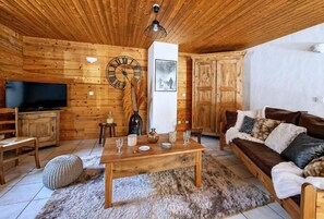 Een houten interieur met een televisie, houten meubels, een klok en een lijst met een afbeelding.