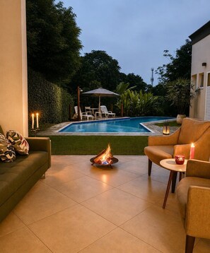 A patio area with a fire feature, outdoor furniture, and a view of a swimming pool.