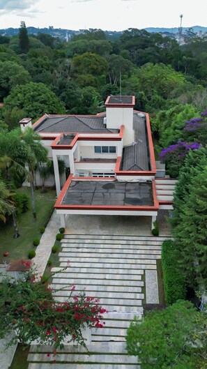 A modern house with a flat roof, a small tower-like structure, and a paved staircase leading to the entrance. - Casa com 4 Quartos - Alto Padrão (Carapicuíba)