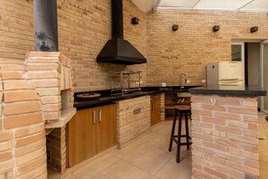 A kitchen with brick walls, a black range hood, and a refrigerator. - Casa com 4 Quartos - Alto Padrão (Carapicuíba)