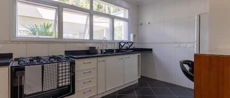 A modern kitchen with a stove, cabinets, and a window overlooking greenery.