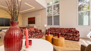 A modern living room with a red vase, two sofas, a round table, and a large window.
