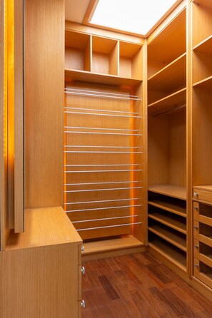 A walk-in closet with wooden shelving, drawers, and a skylight.