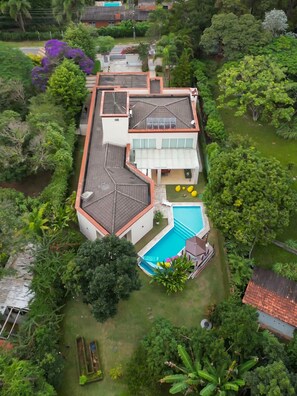 A two-story house with a swimming pool, surrounded by lush greenery. - Casa com 4 Quartos - Alto Padrão (Carapicuíba)