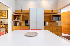 A modern kitchen with white cabinets, wooden shelves, and a central island. - Casa com 4 Quartos - Alto Padrão (Carapicuíba)