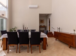 Un comedor con una mesa dispuesta para cuatro personas, un aparador de madera y una escalera que lleva a otra habitación.