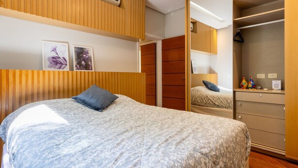 A bedroom with a bed, a dresser, a mirror, and a wardrobe.