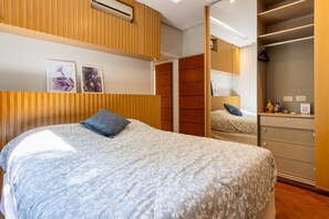Un dormitorio con cama, cómoda, espejo y armario.