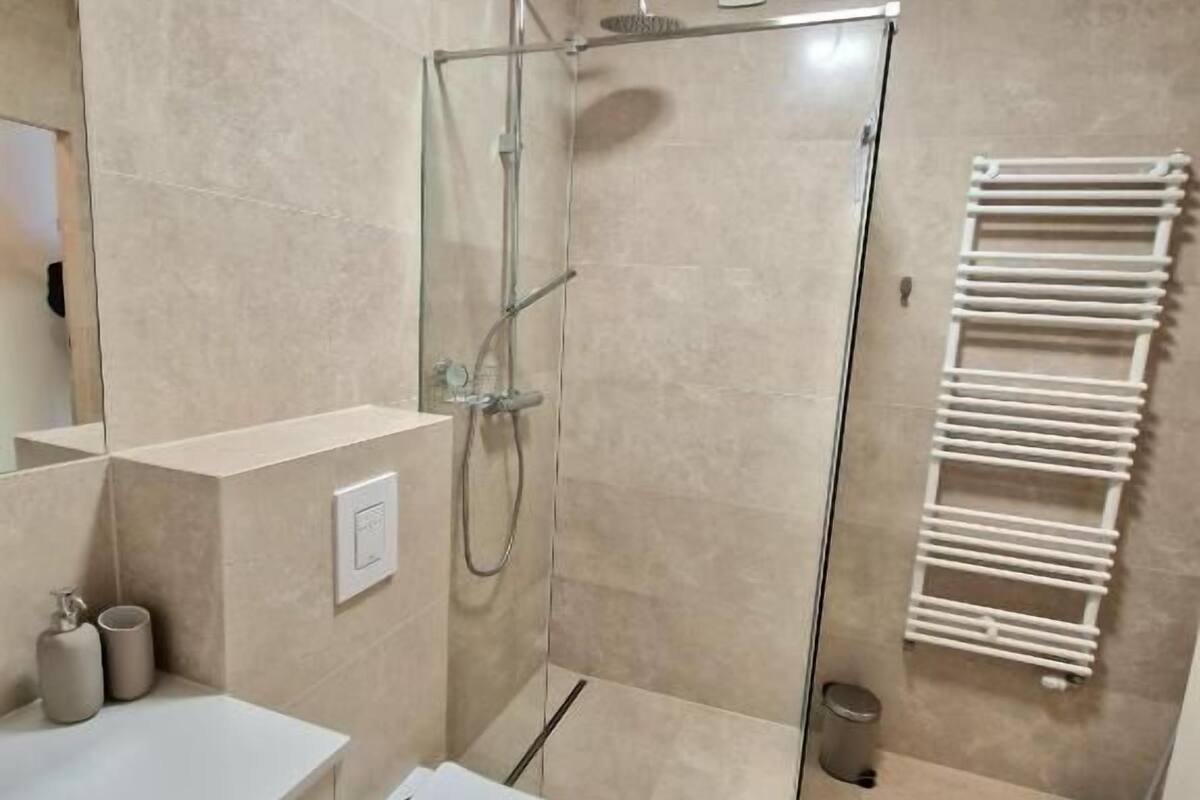 Une salle de bain moderne avec une douche à parois de verre, des toilettes blanches et un porte-serviettes.
