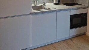 Una cocina moderna con un fregadero, hervidor y estufa.
