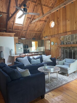 Ein Blockhaus-Interieur mit Wohnzimmer, Essbereich und Kamin aus Stein.