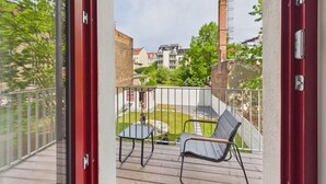 A balcony with two chairs, a view of a residential area, and a brick chimney. - Group apartment with balcony, up to 5 persons - GÖ07 (Görlitz)